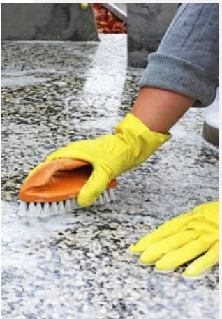 Using a brush and water to clean a granite headstone