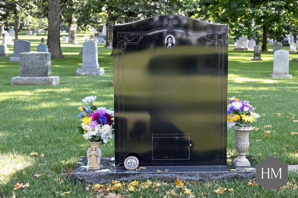 Headstone in a cemetery with flowers either side