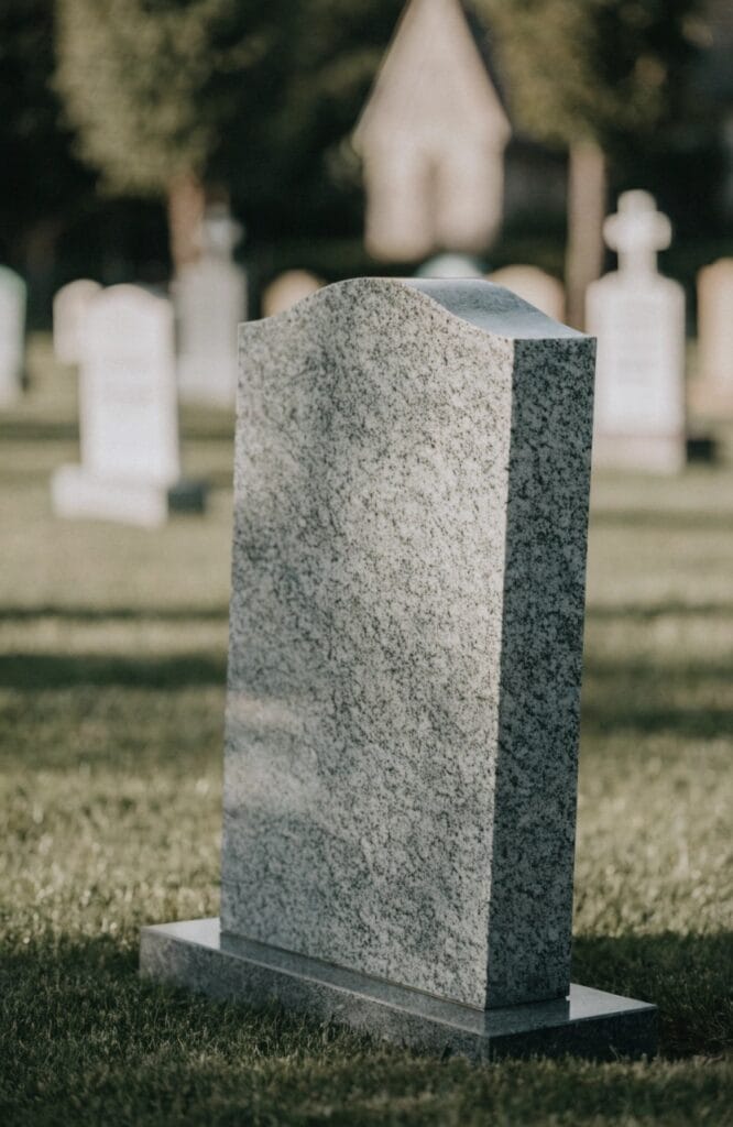 grey granite headstone in a peaceful churchyard, soft natural light on green grass